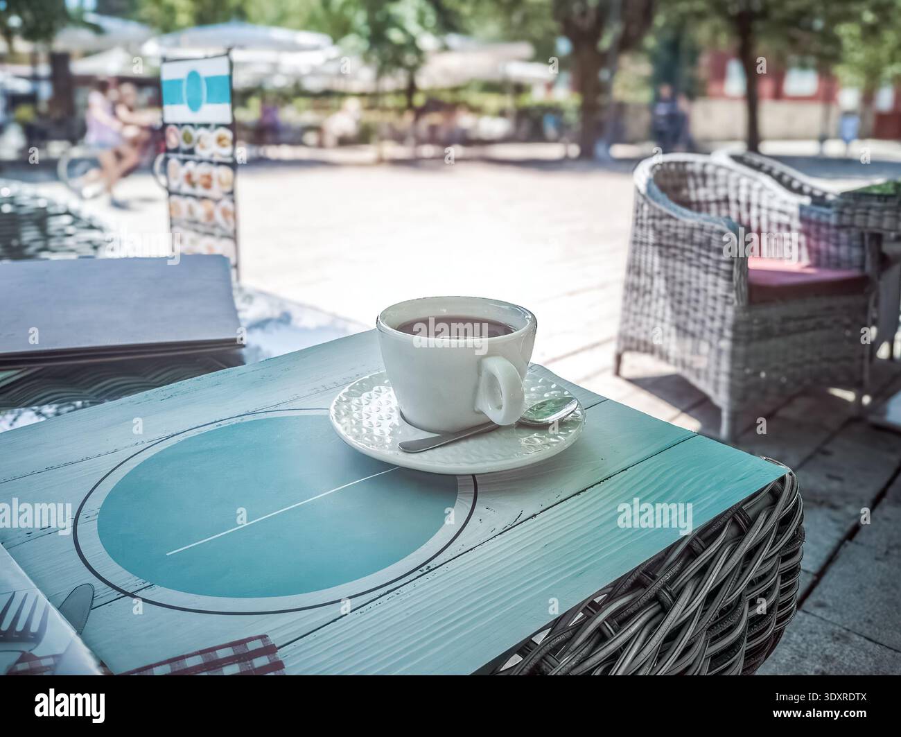 Morning coffee on a stylish cafe terrace in Cetinje. A white cup of espresso on a modern table design with a blurred summer street in Montenegro - Smartphone Captured Stock Image