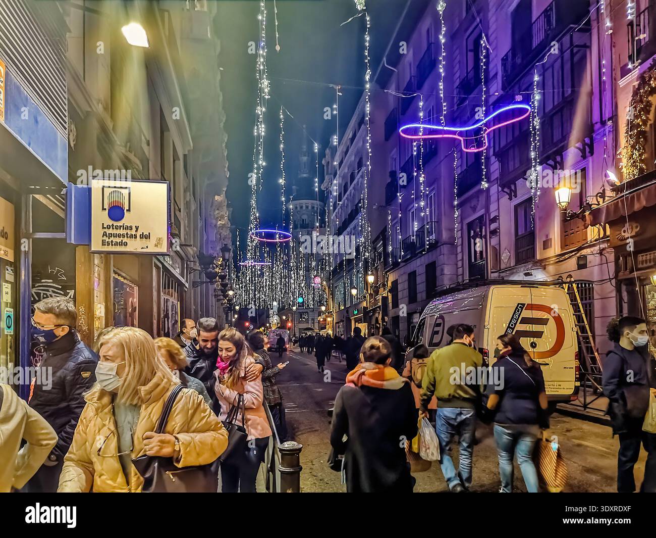 Street in Madrid during the holiday season, decorated with festive lights as people walk along the busy sidewalk. Madrid, Spain - November 30, 2021 - Smartphone Captured Stock Image