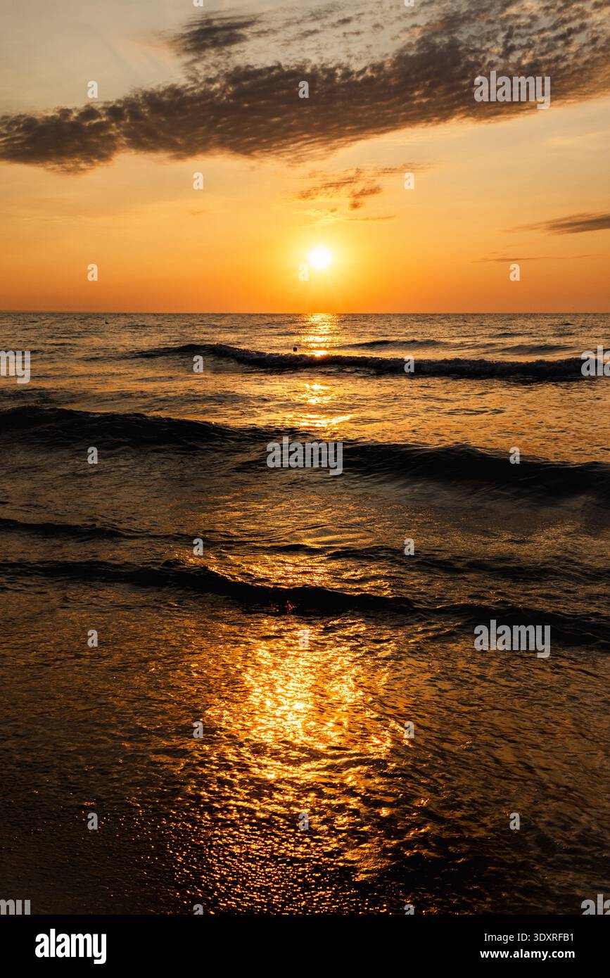 Golden sunset over ocean with waves and bright sunlight reflection on ...