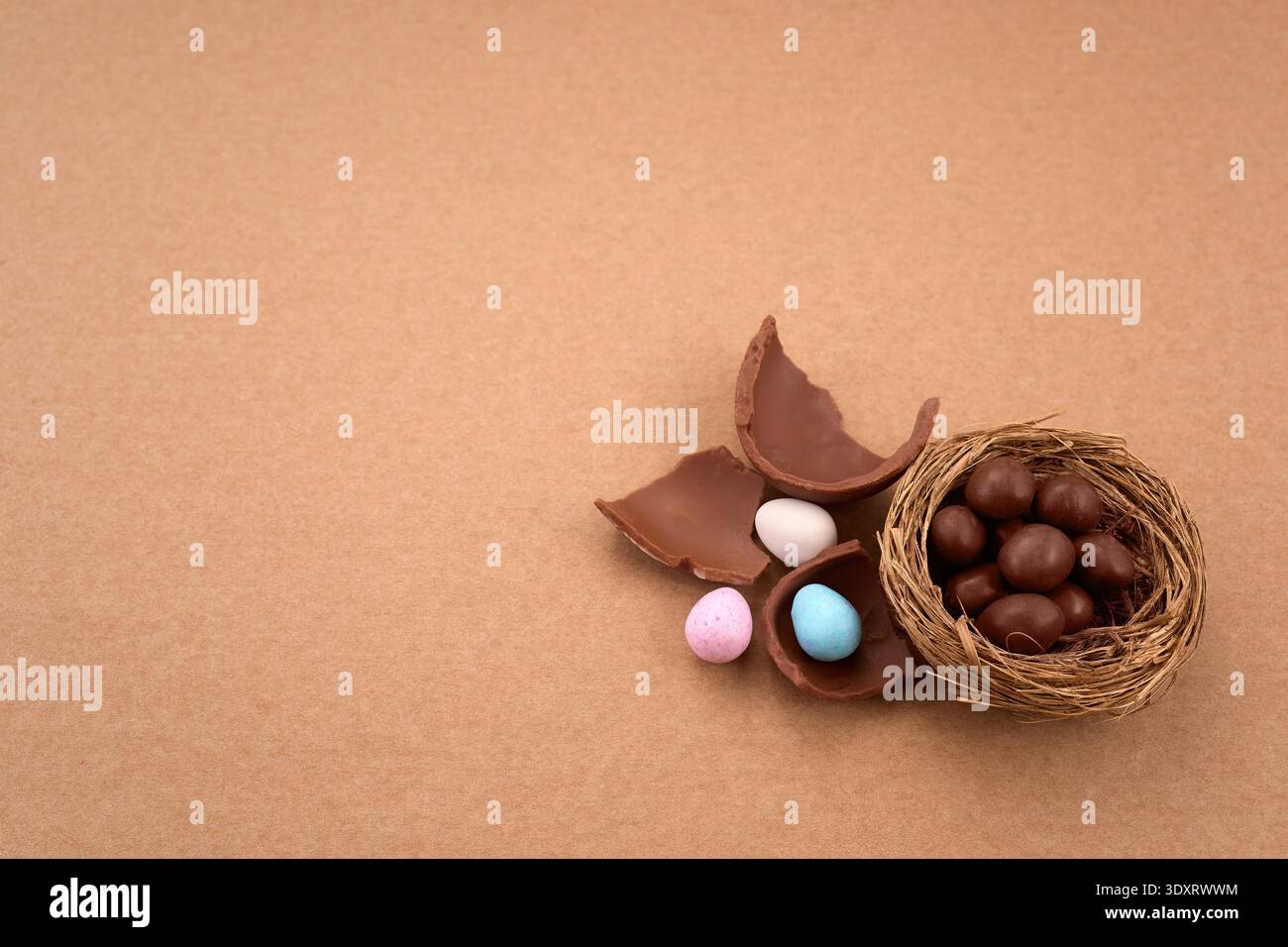 Chocolate easter eggs and nest with candy on brown background Stock Photo