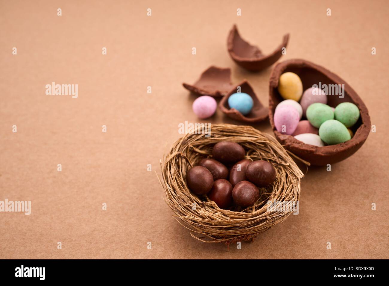 Chocolate easter eggs and nest with candy on brown background Stock Photo