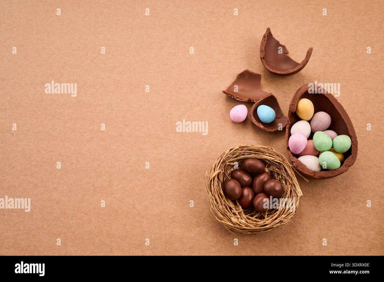 Chocolate easter eggs and candy scattered on brown background Stock Photo