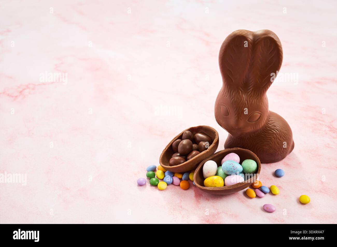 Chocolate easter bunny with candy eggs on pink marble Stock Photo