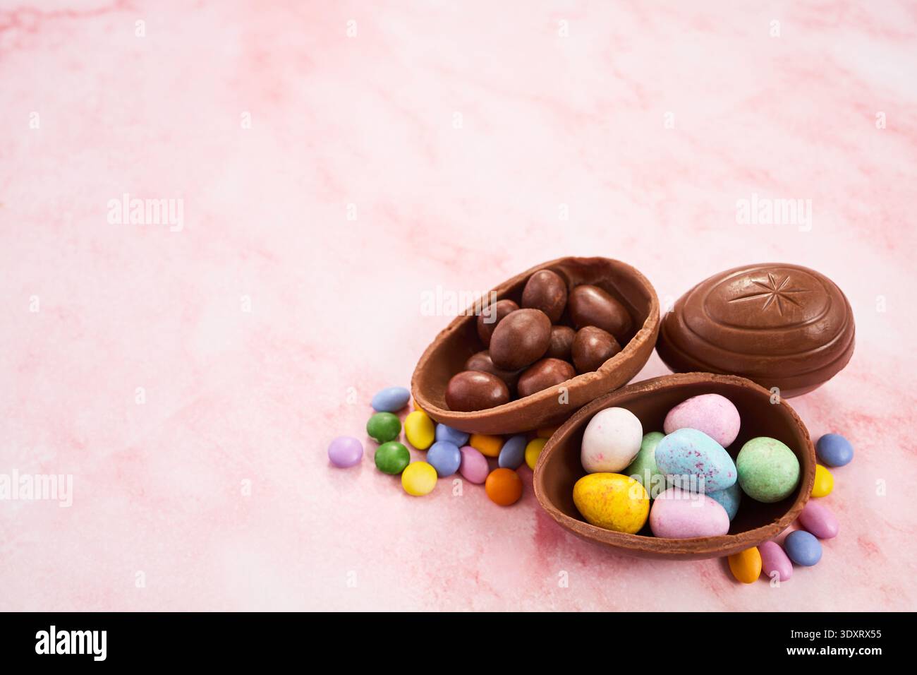 Easter chocolate egg candy spilling on pink background Stock Photo