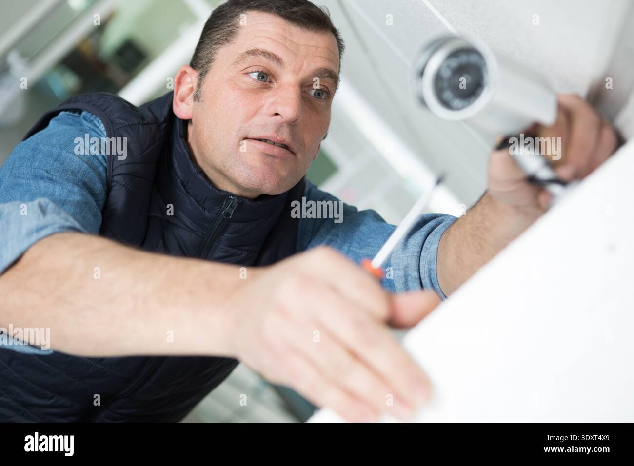 technician installing cctv camera on wall indoors Stock Photo