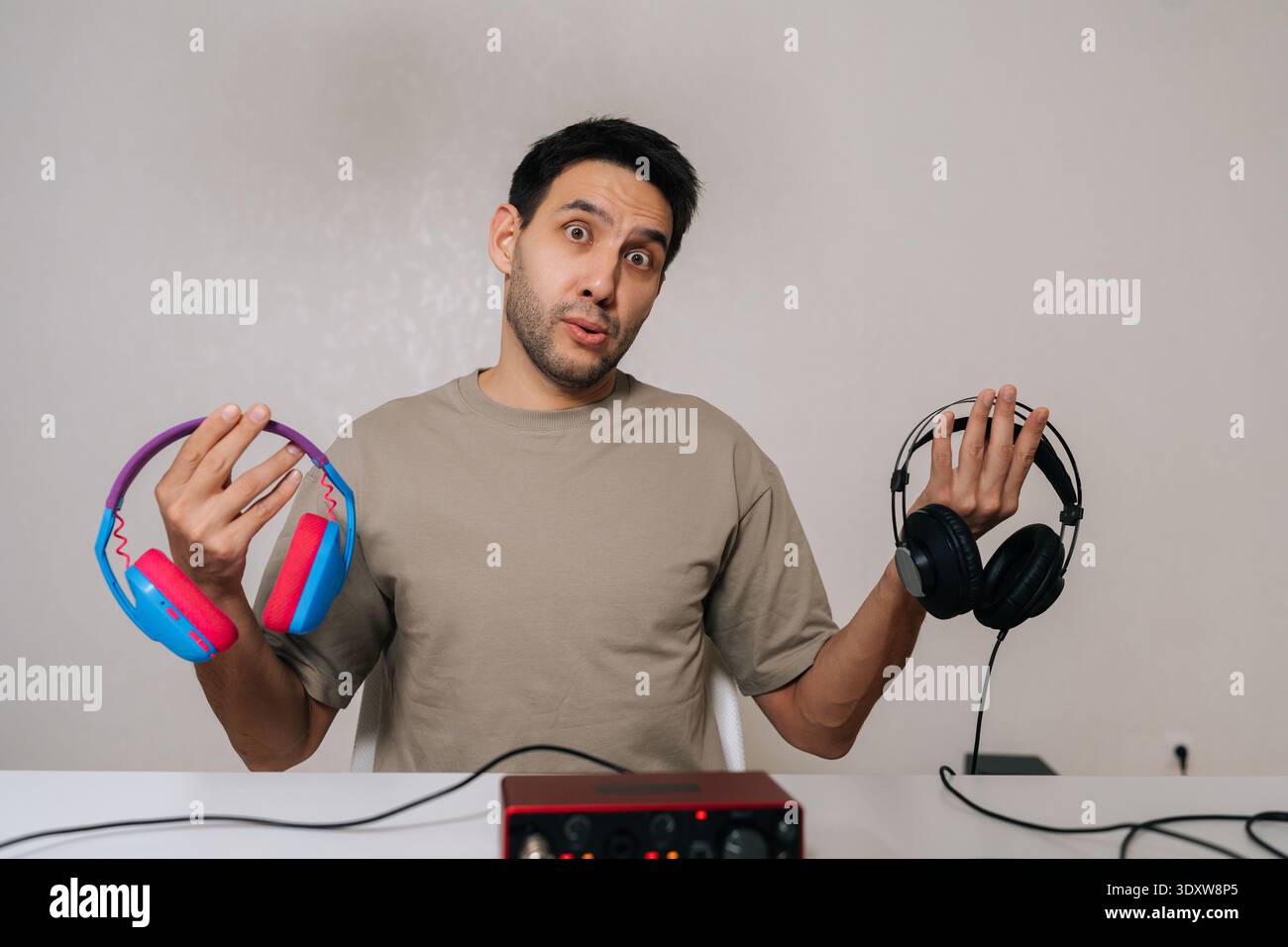 Funny excited man comparing two distinct headphones, considering ...