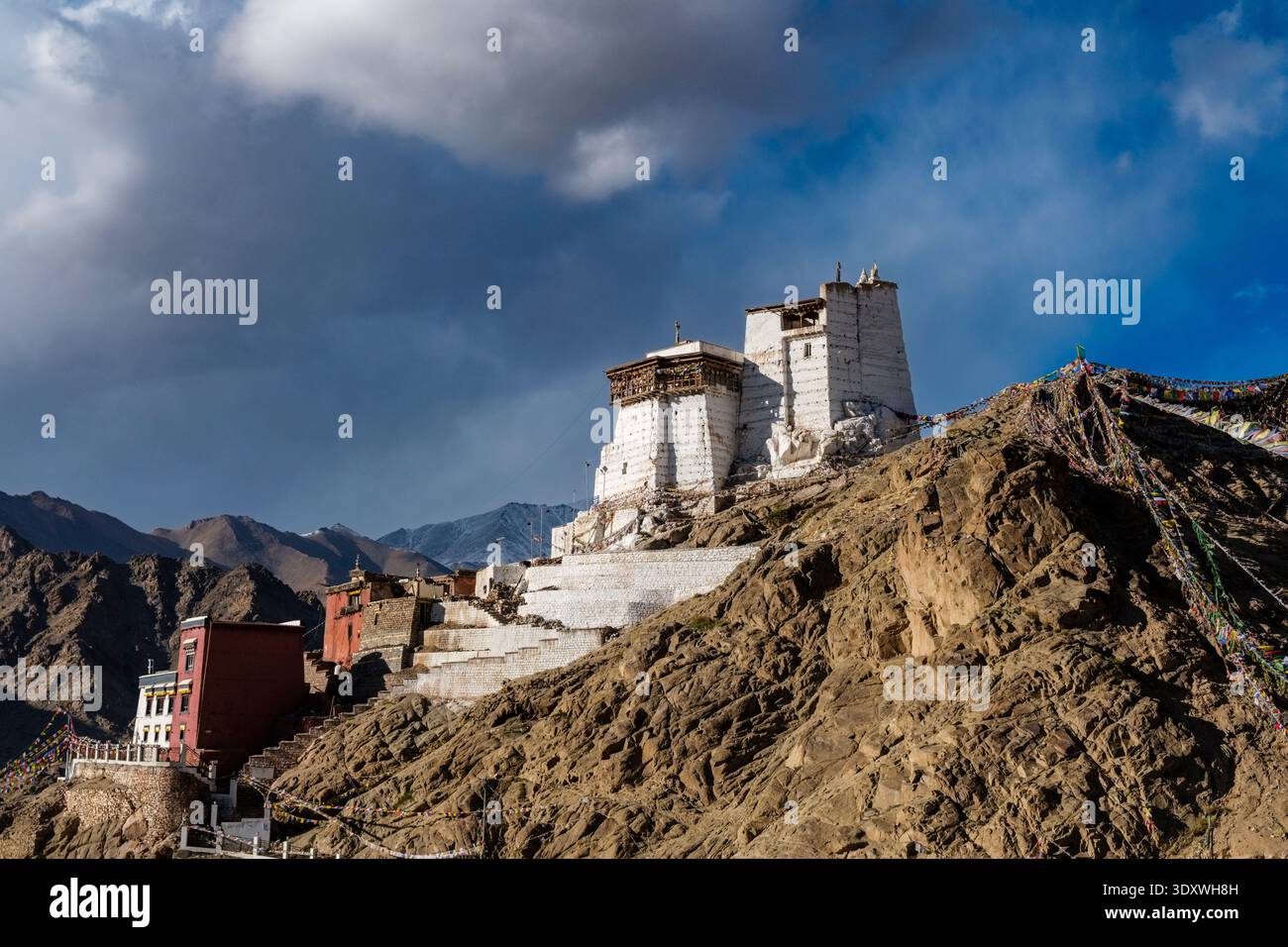 The historic Tsemo Castle and Namgyal Tsemo Monastery stand atop a steep mountain ridge in Leh, adorned with numerous prayer flags. Stock Photo