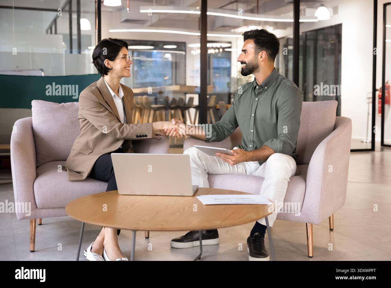 Smiling business people shaking hands in office Stock Photo