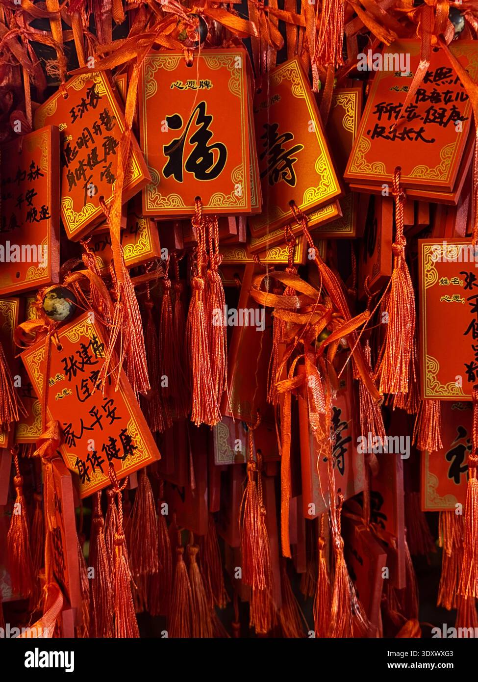 Red Chinese prayer tags with wishes and calligraphy hanging at temple, traditional symbols of luck and fortune, China. - Smartphone Captured Stock Image