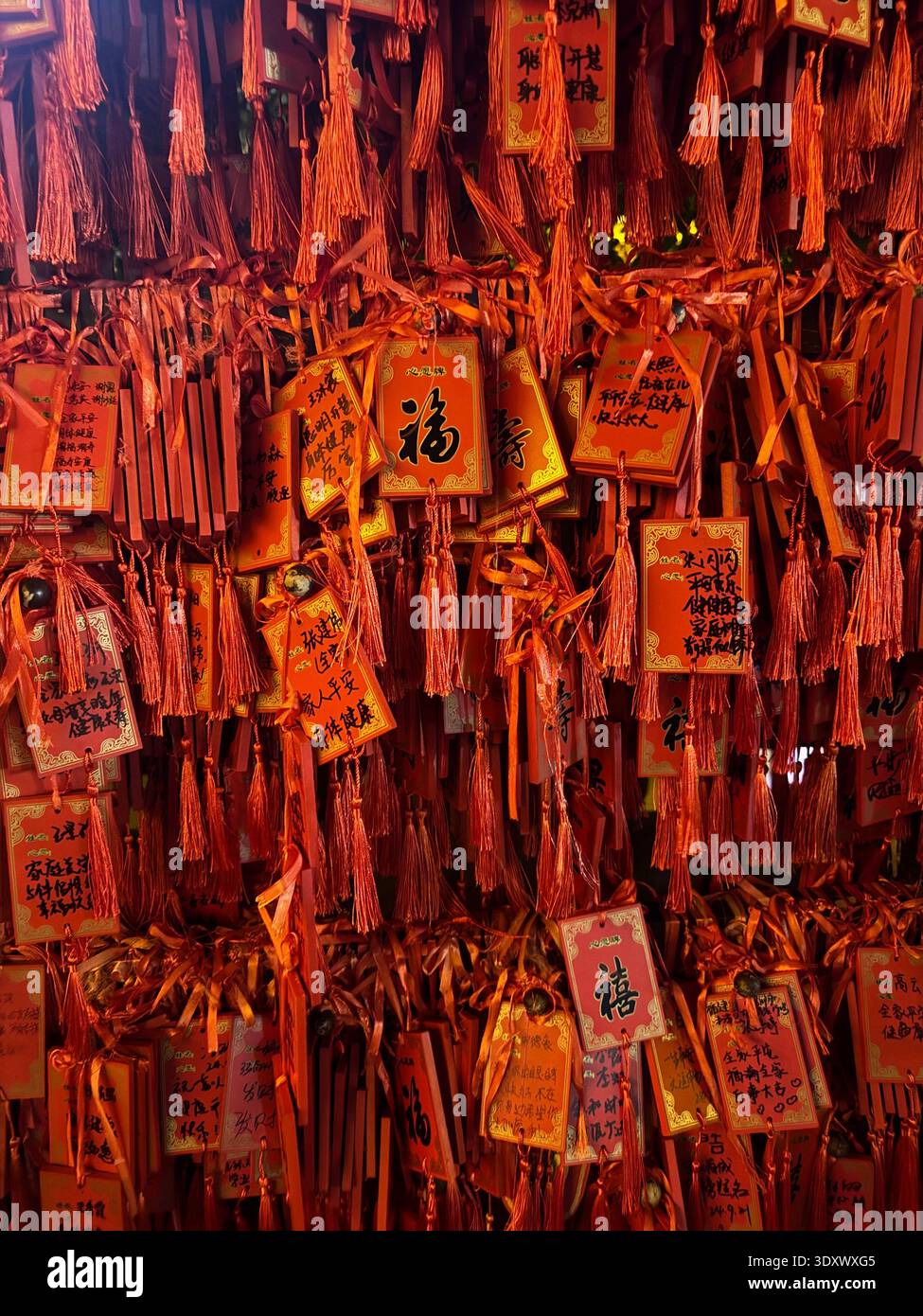 Red Chinese prayer tags with wishes and calligraphy hanging at temple, traditional symbols of luck and fortune, China. - Smartphone Captured Stock Image