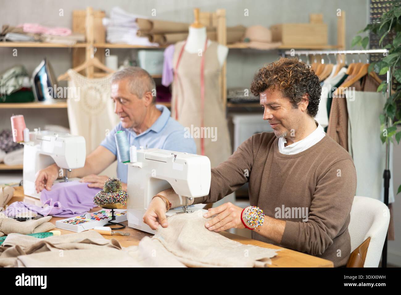 Two tailors sitting in a sewing workshop and working Stock Photo