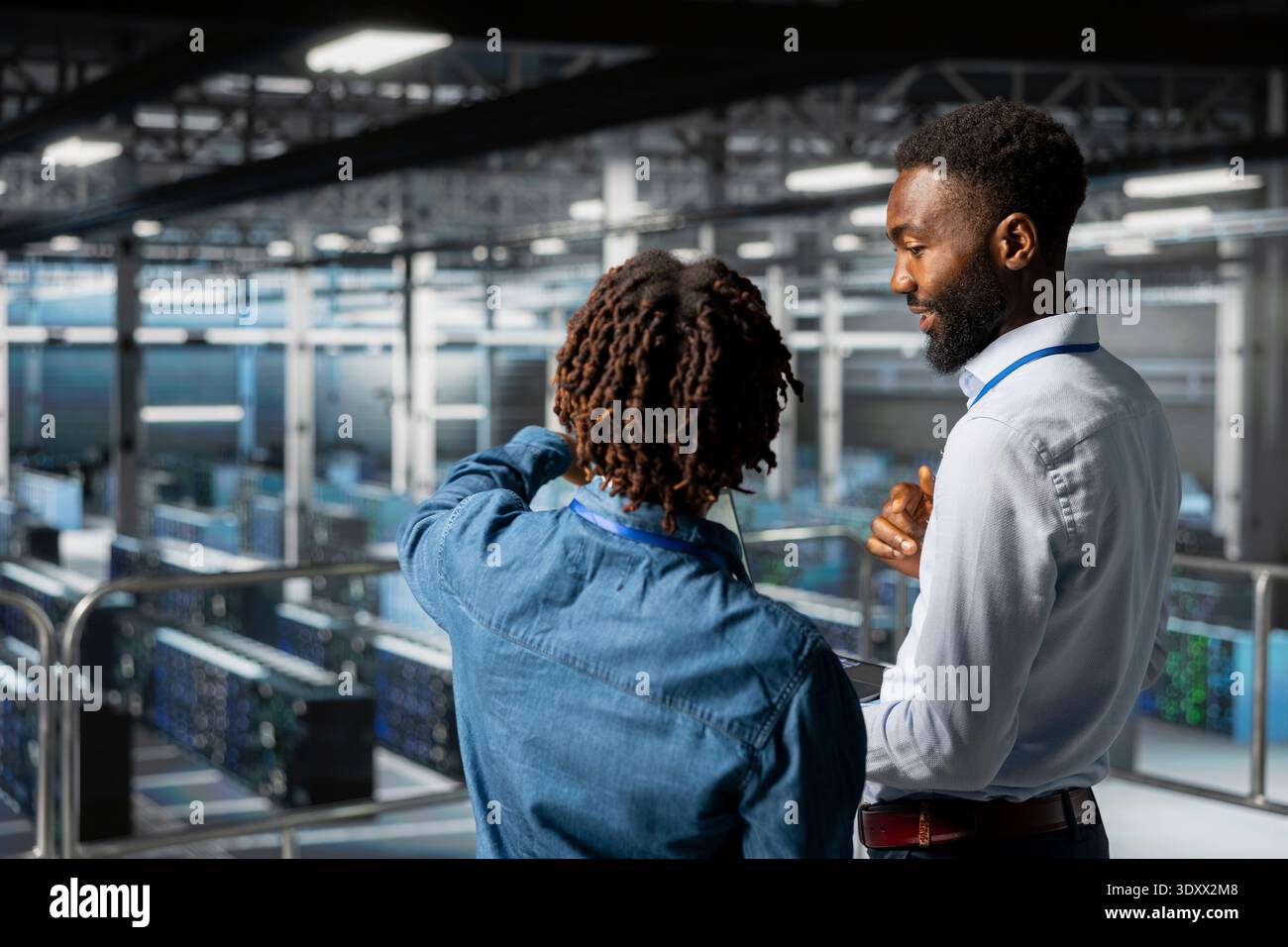 Black data center engineering team on industrial platform collaborating for server management, server rigs innovation. Technicians coordinating infrastructure tasks to support machine learning. Stock Photo