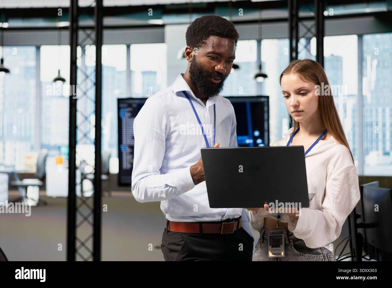 Manager helping young trainee coding during internship in tech startup using laptop. Team leader providing support to newcomer engineer using notebook in software development agency Stock Photo