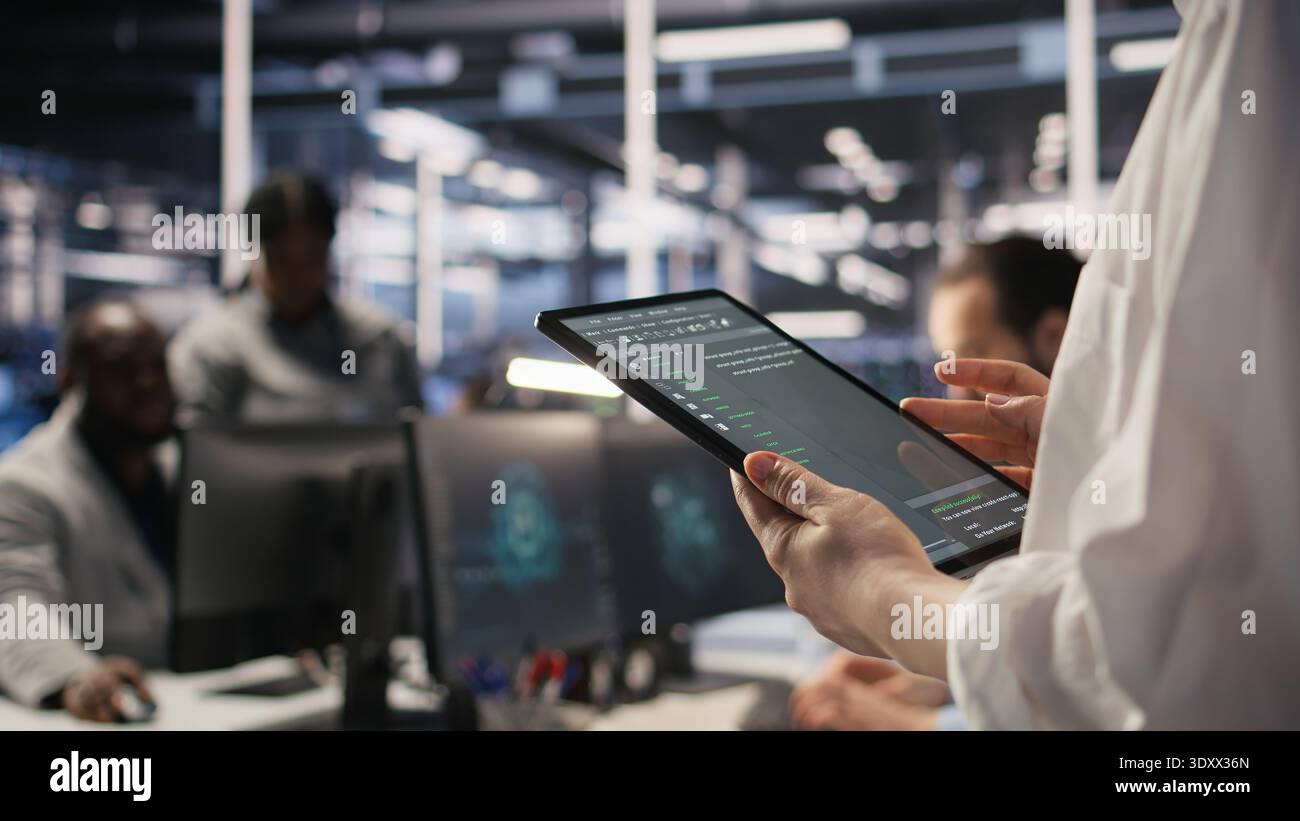 Close up of data center system administrator coding on tablet, doing software updates. Server room IT expert looking at device screen, optimizing infrastructure rackmounts configuration rigs, camera A Stock Photo