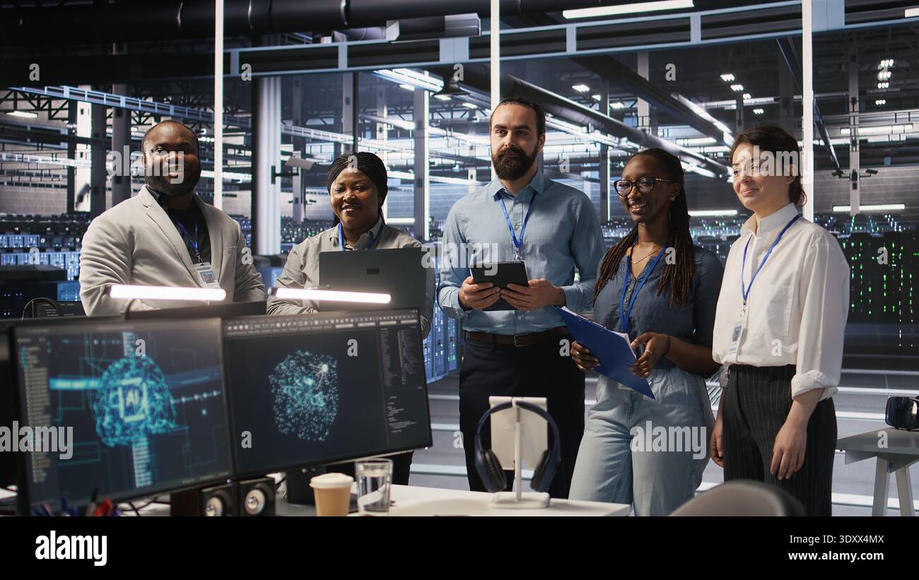 Happy data center engineering team members collaborating on neural network software development. Smiling server hub coworkers implementing machine learning technology in workplace, camera A Stock Photo