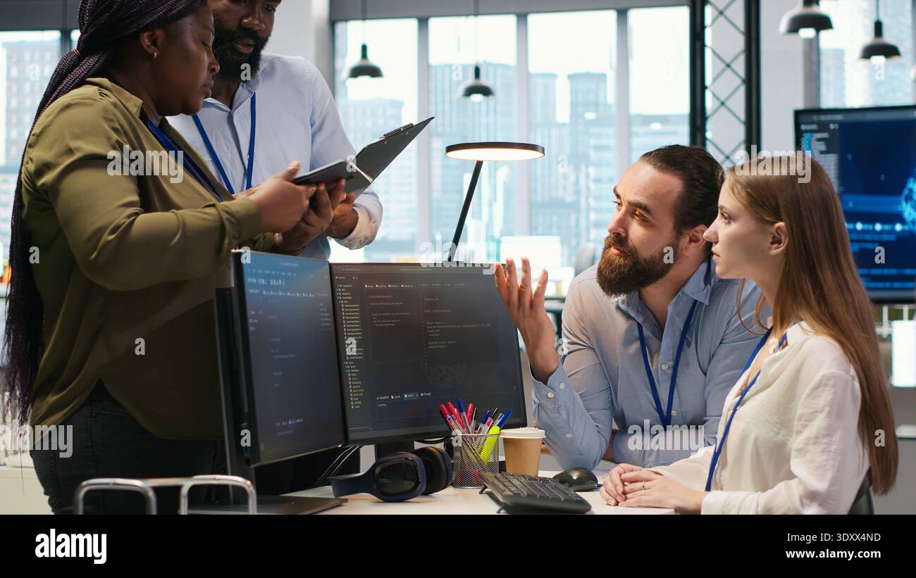 Teamworking programmers developing software applications, working together to optimize code. Tech startup team doing brainstorming in office, using AI to solve bottlenecks, camera A Stock Photo
