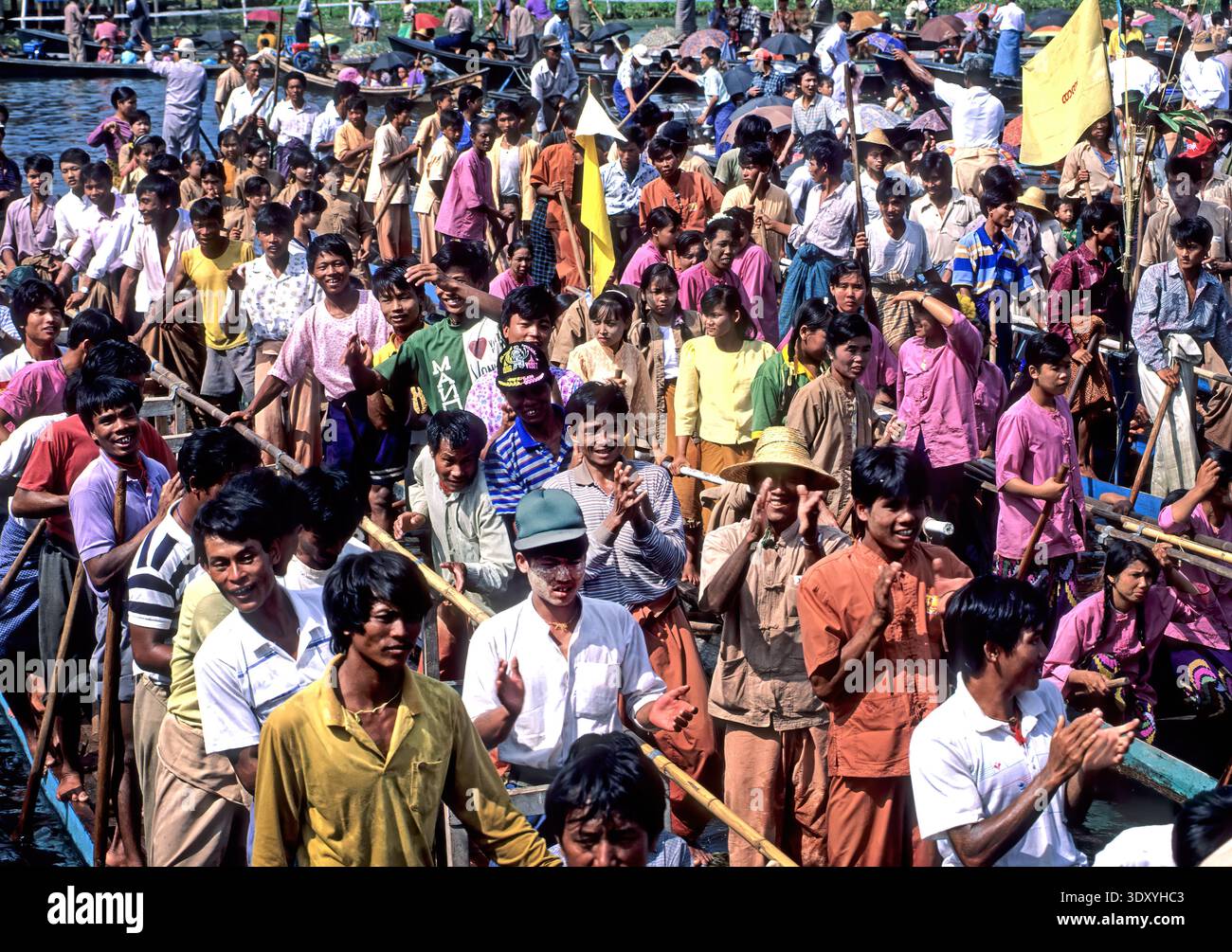 People gather on boats during the Inle Lake Festival in Myanmar. Joyful participants celebrate with music and clapping in the lively atmosphere. Stock Photo