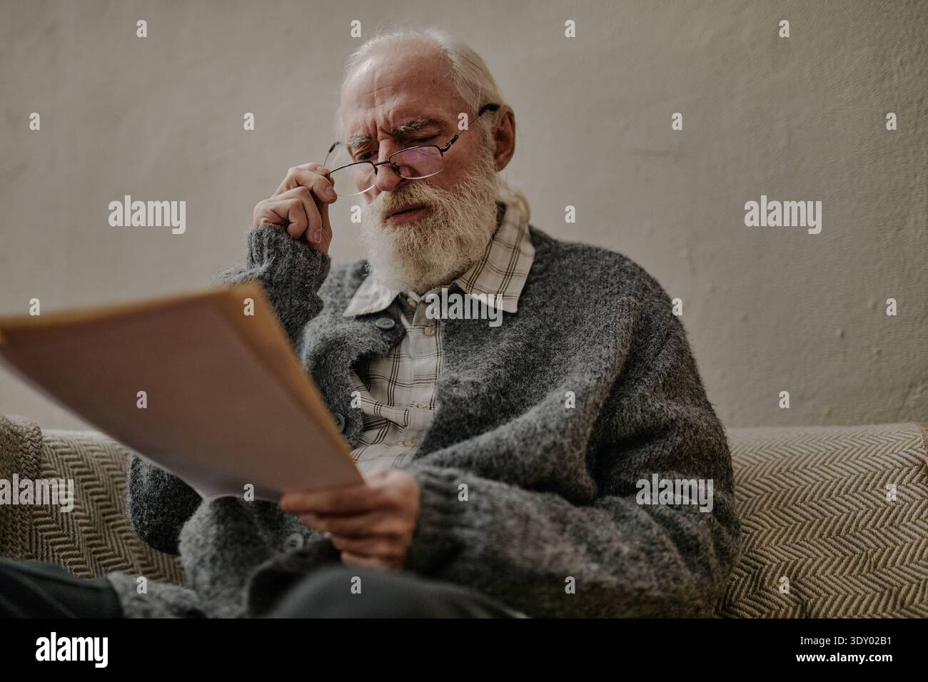 Senior Caucasian Man Reading Documents While Sitting Indoors on Sofa Stock Photo