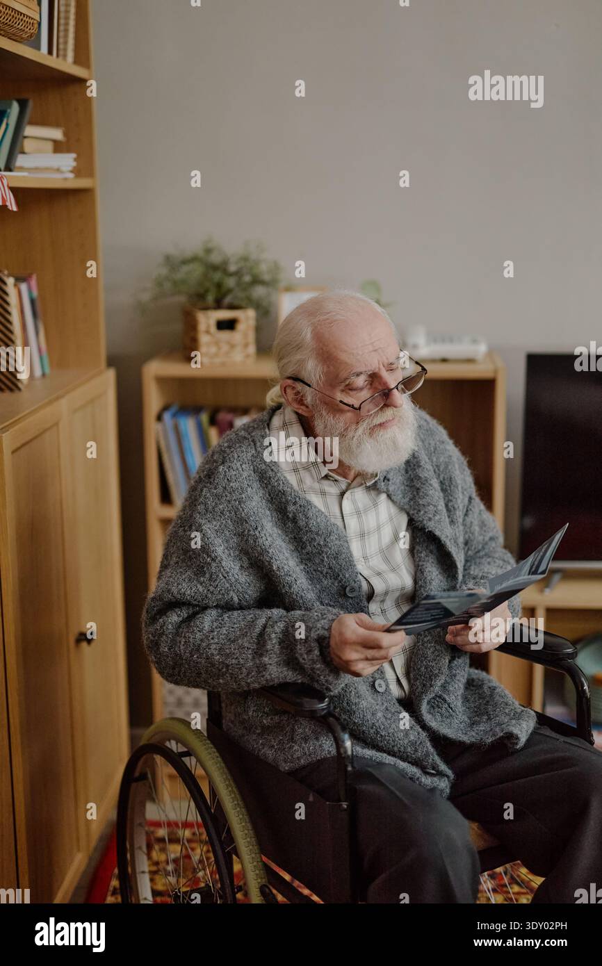 Senior Caucasian Man with Disability Reading Document at Home Stock Photo