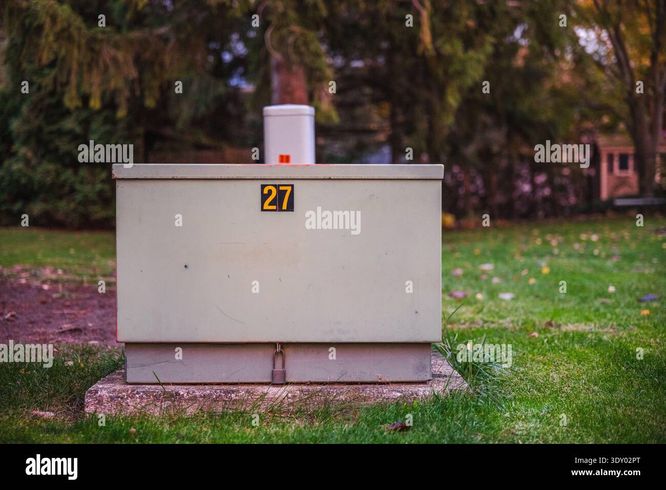 Power distribution box on a green lawn in a suburban area at dusk Stock Photo