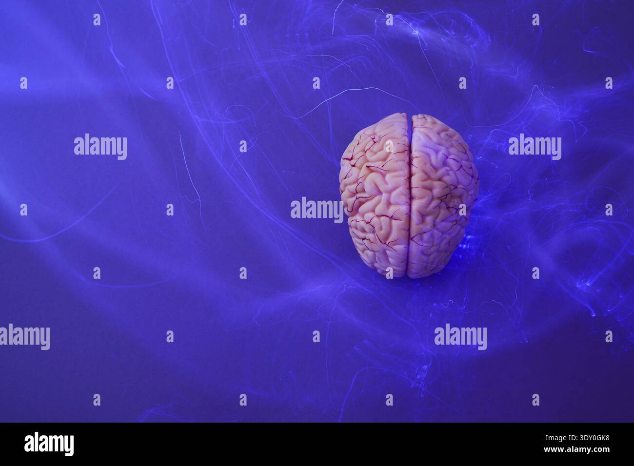 Brain model generating neural impulses on blue background Stock Photo