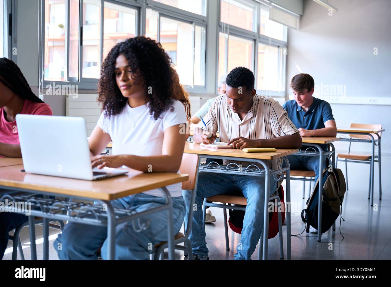 Focused students using laptop and writing in classroom Stock Photo