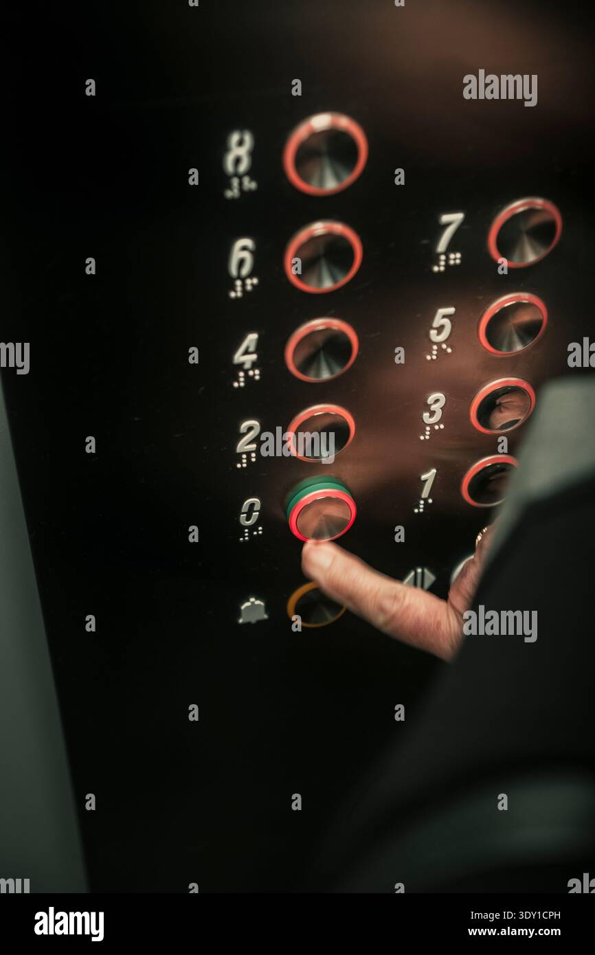 Close up of senior woman hand pressing an elevator button with braille numbers. Stock Photo