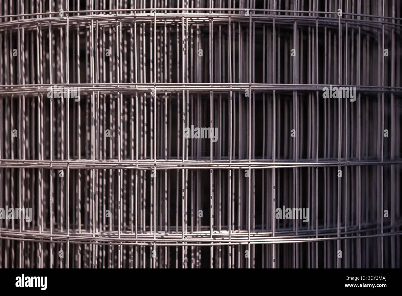 Rolled welded wire mesh fencing material creating abstract geometric pattern Stock Photo