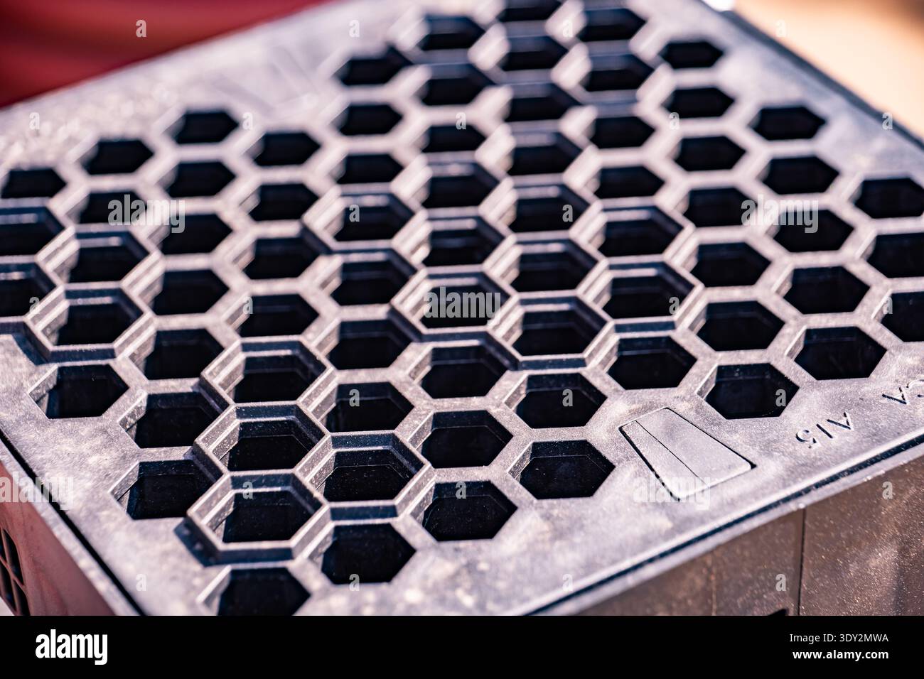 Repeating honeycomb pattern creating textured grid on black plastic surface Stock Photo