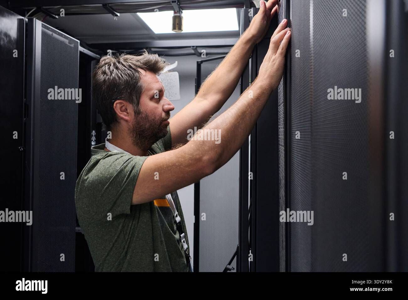 IT technician inspecting server rack in data center performing maintenance and hardware installation Stock Photo