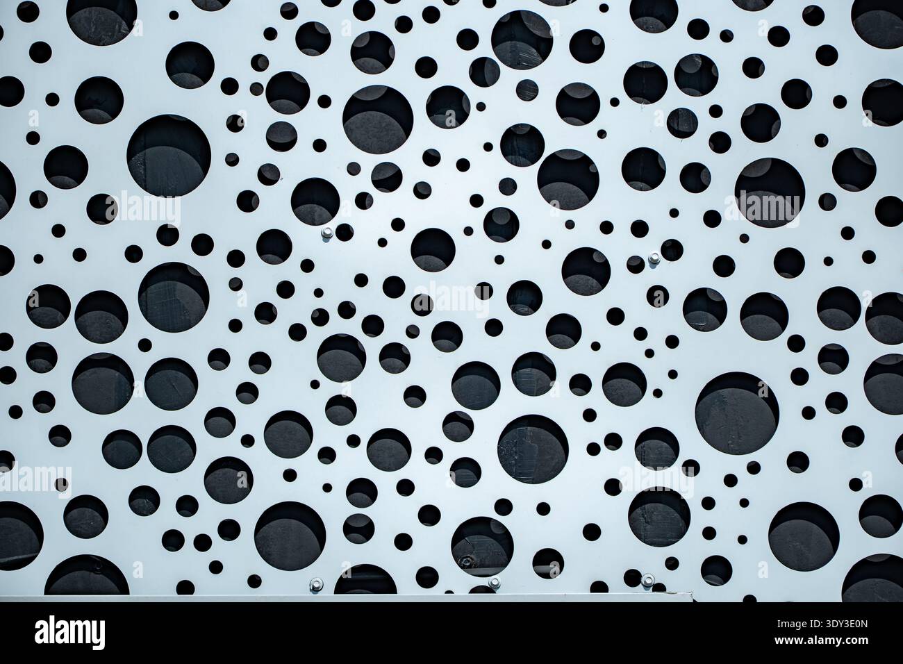 Perforated metal panel creating a contemporary abstract circle background Stock Photo