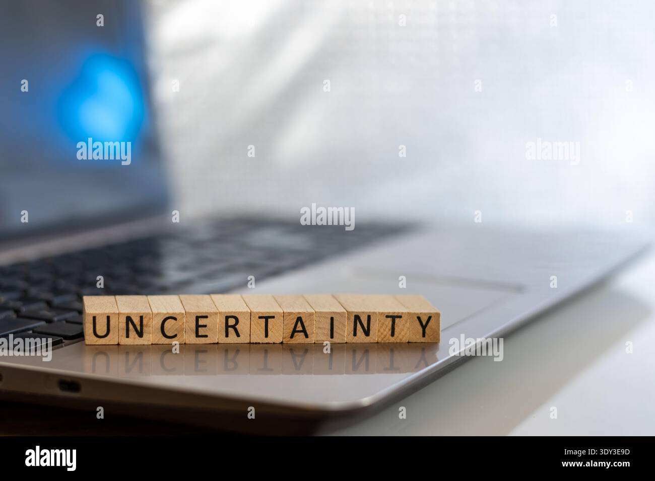 Uncertainty financial and forward-looking future business concept with wooden blocks on laptop silver blue bokeh copy space Stock Photo