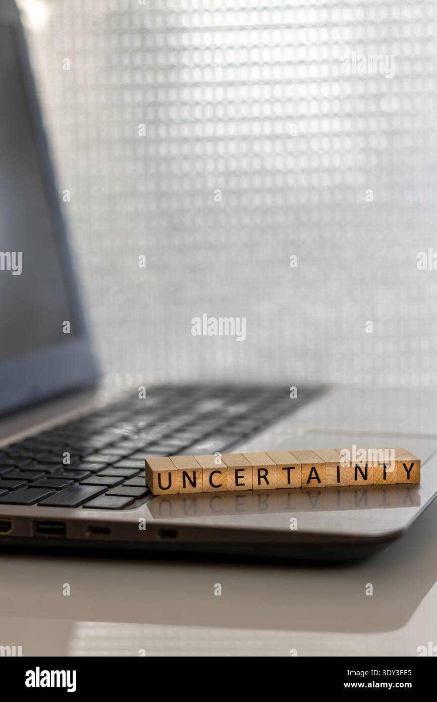 Uncertainty financial and forward-looking future business concept with wooden blocks on laptop silver blue bokeh copy space Stock Photo