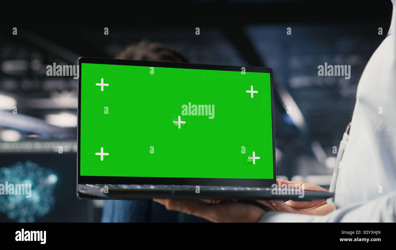 Close up of data center employee doing maintenance tasks on green screen laptop, ensuring optimal performance. Worker using mockup notebook to review diagnostics and apply patches Stock Photo