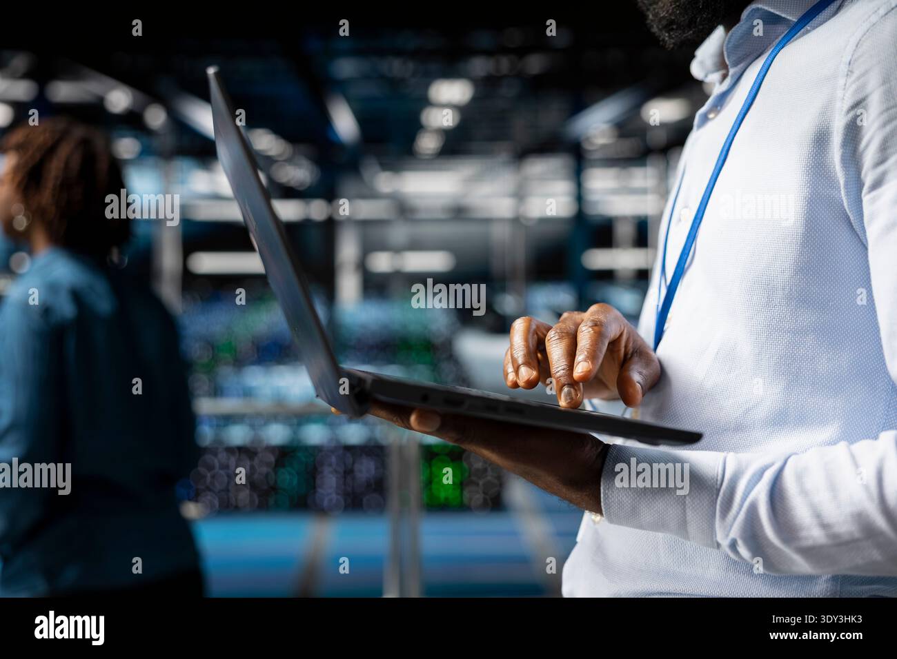 Close up of data center software engineer doing maintenance work on laptop, ensuring optimal performance. Male worker reviewing diagnostics and debugging server hub high tech equipment. Stock Photo