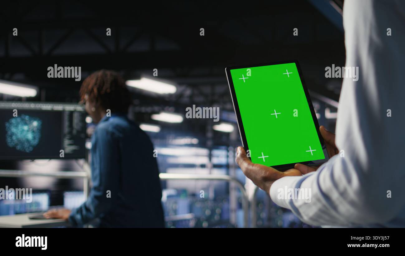 Data center engineers on industrial platform using isolated screen device, collaborating on tasks. Server hub workers visualizing large language model architecture using chroma key tablet Stock Photo