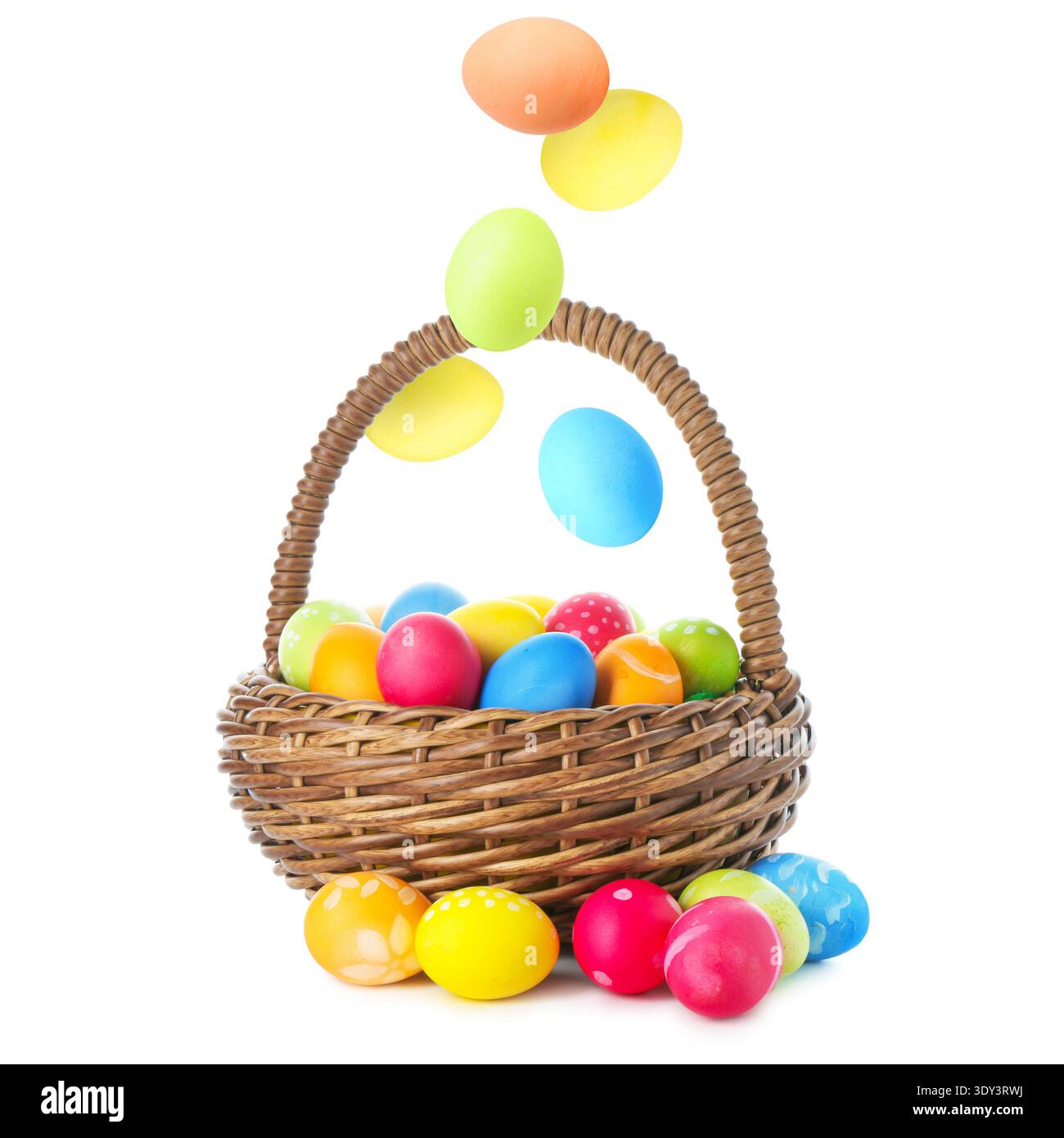 Bright Easter eggs falling into basket on white background Stock Photo