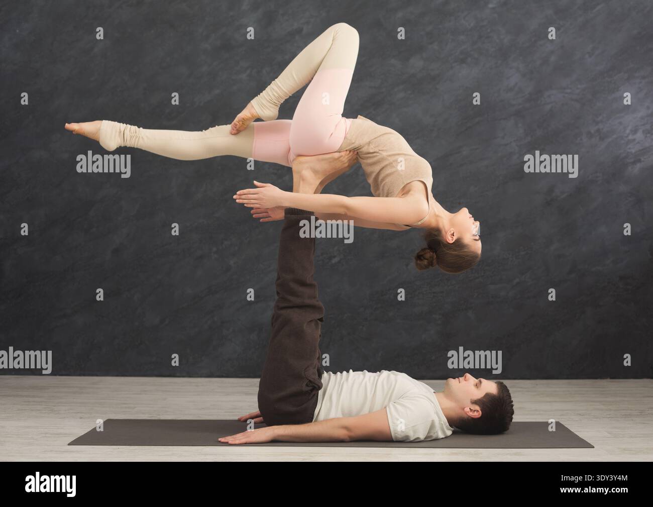 Young couple practicing acroyoga on mat together Stock Photo