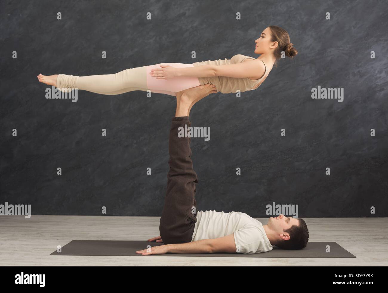 Young couple practicing acroyoga on mat together Stock Photo