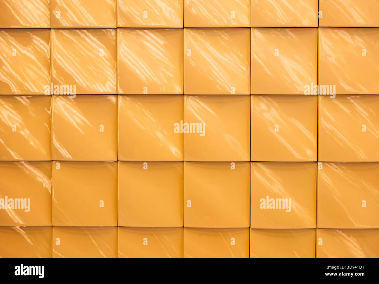 Yellow glossy ceramic tile wall with square pattern and light reflections Stock Photo