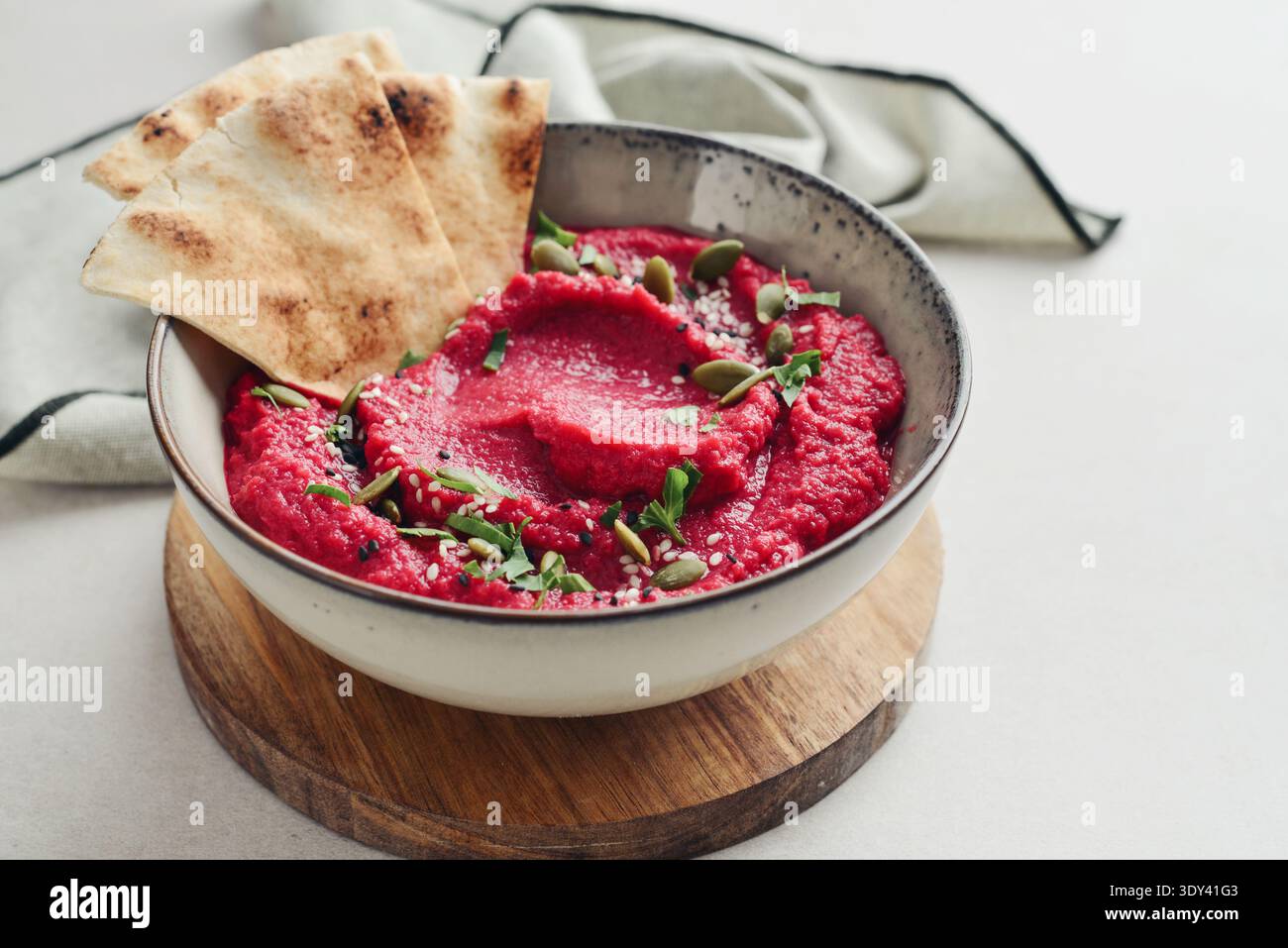 Beetroot hummus decorated with sesame and pumpkin seeds  in bowl with pita bread on gray stone background,  closeup Stock Photo