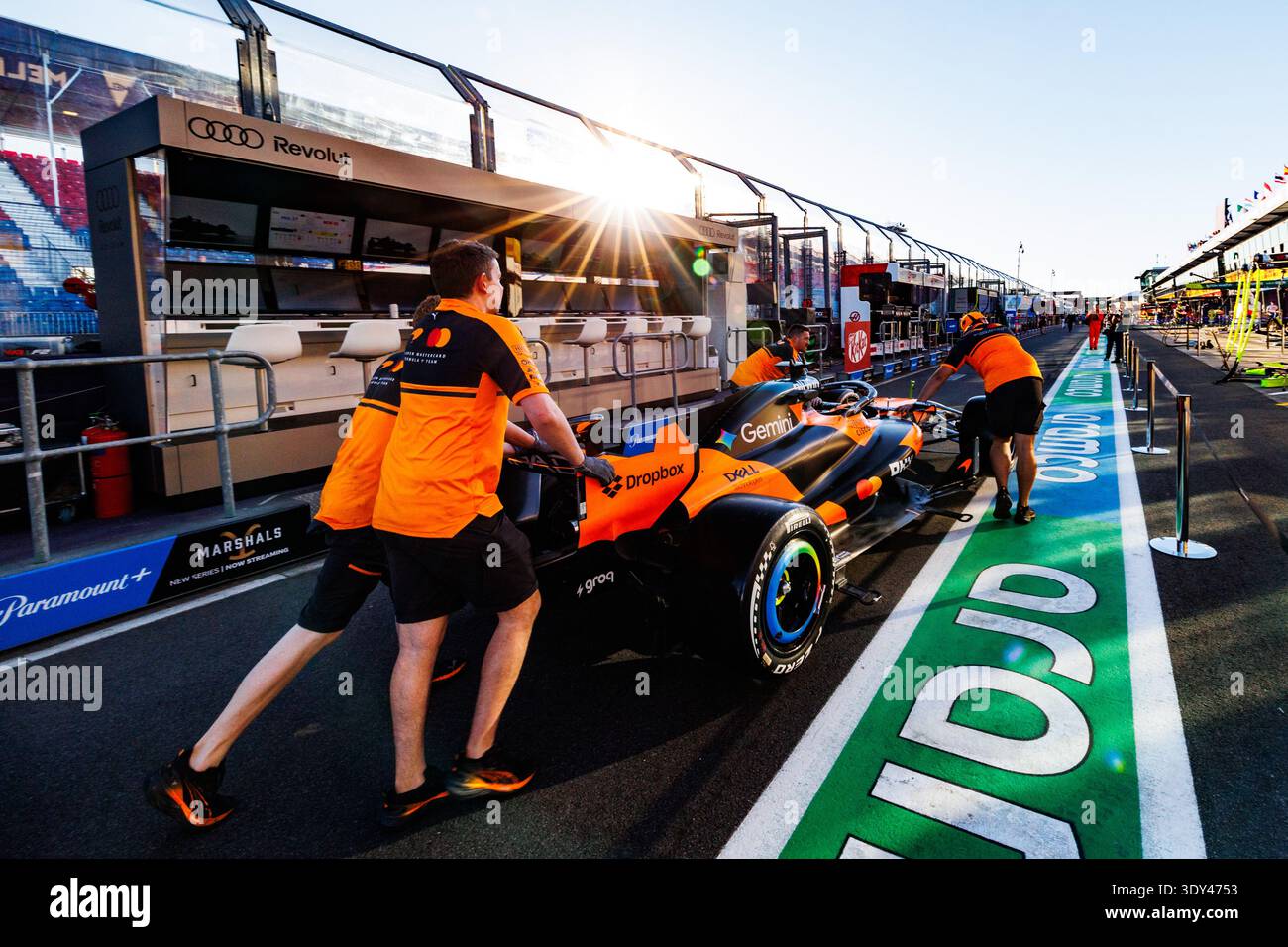 Members of the McLaren Formula 1 Team push the car down pit lane ...