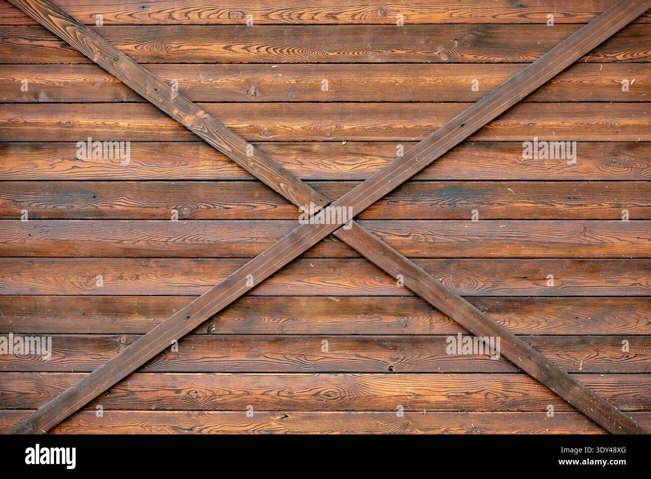 Rustic brown wood paneling creating an X pattern on a barn door texture Stock Photo