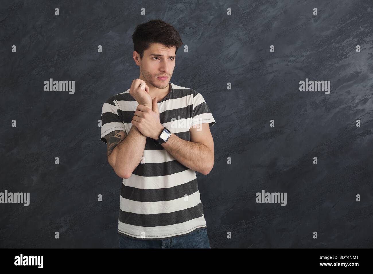Pensive young man with smartwatch in studio Stock Photo