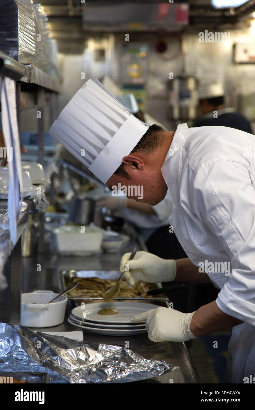 Chef plating a dish with sauce in kitchen Stock Photo