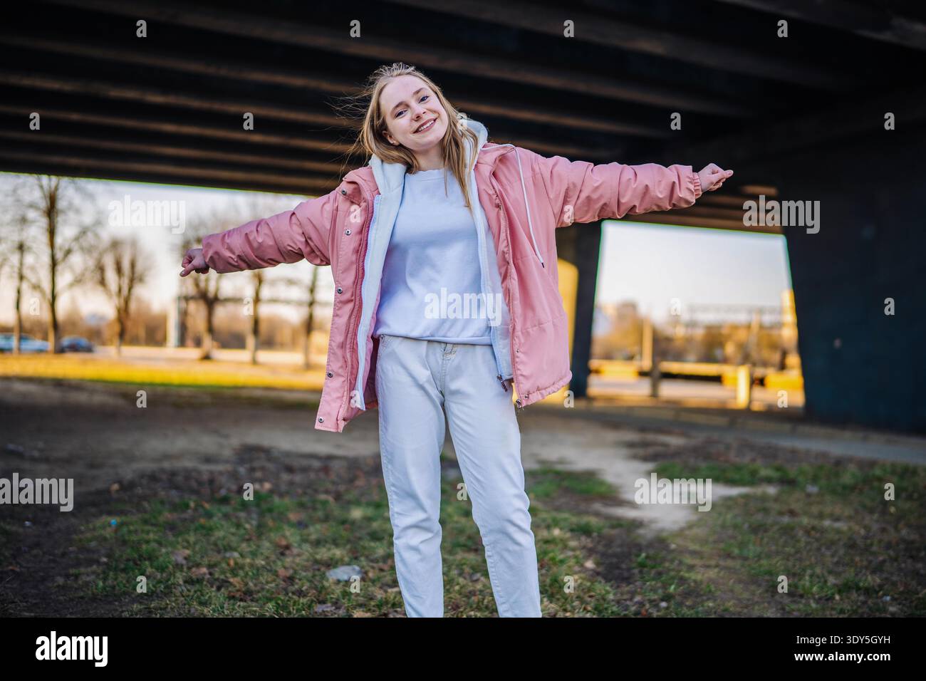 Young woman enjoying freedom, smiling with arms wide open in urban setting Stock Photo