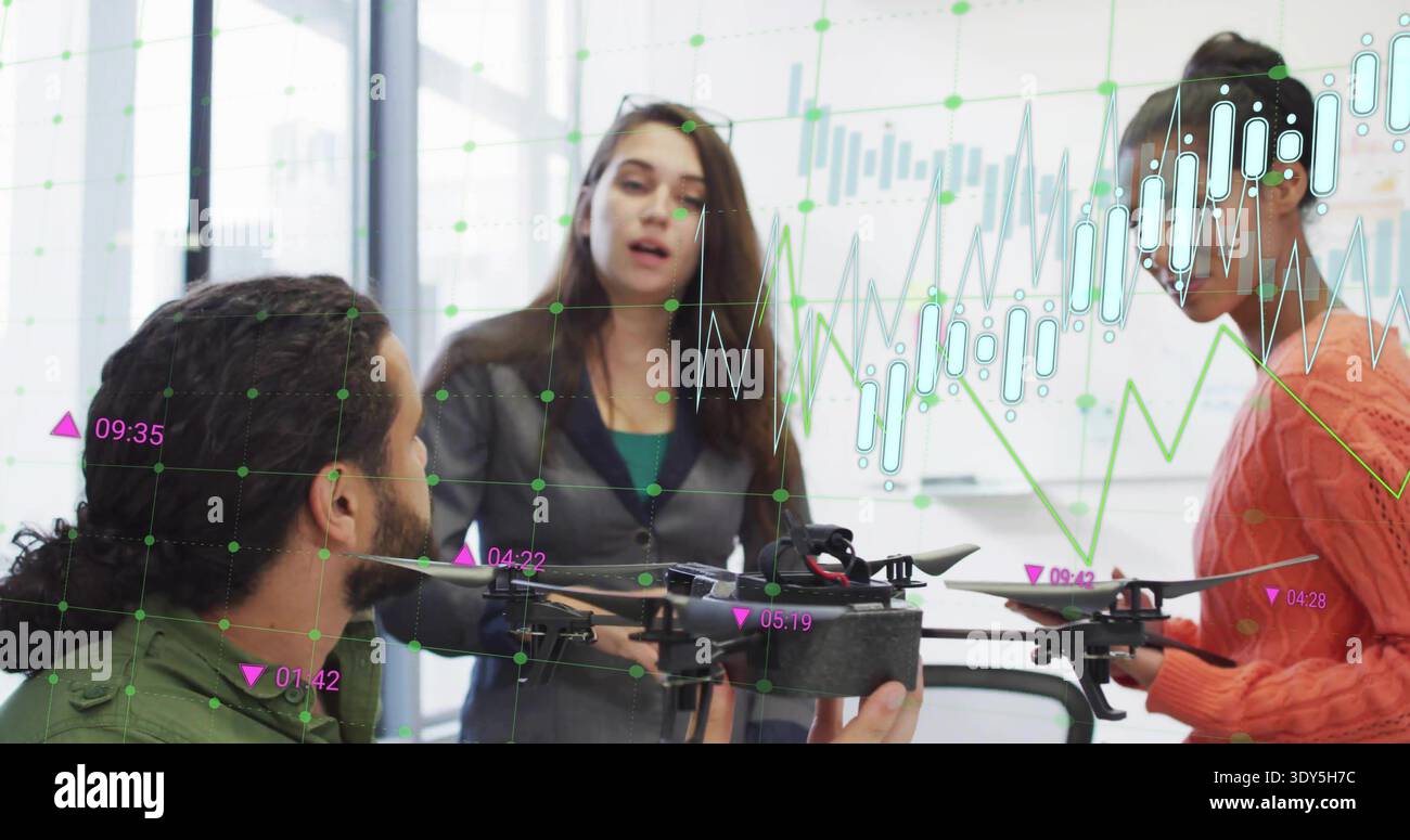 Presenting three team members discussing drone in meeting room, gray blazer gesturing, charts Stock Photo