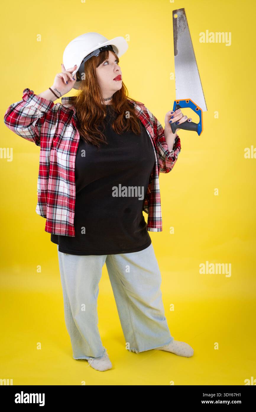 Woman worker thinking while holding hand saw Stock Photo