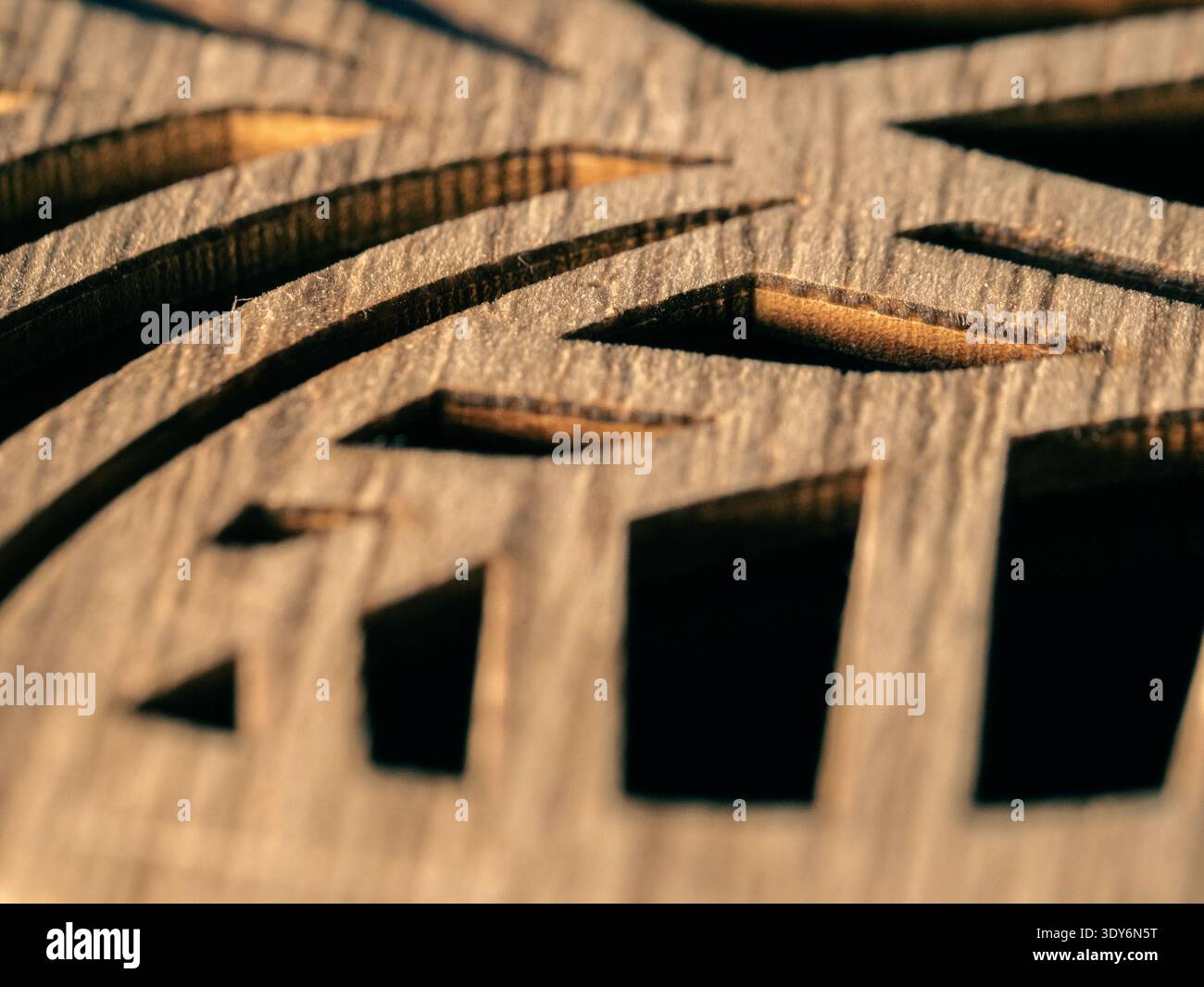 Wood grain shows intricate carved patterns. Light highlights texture and depth in each cut. Geometric shapes form a rhythmic, artistic design. Natural Stock Photo