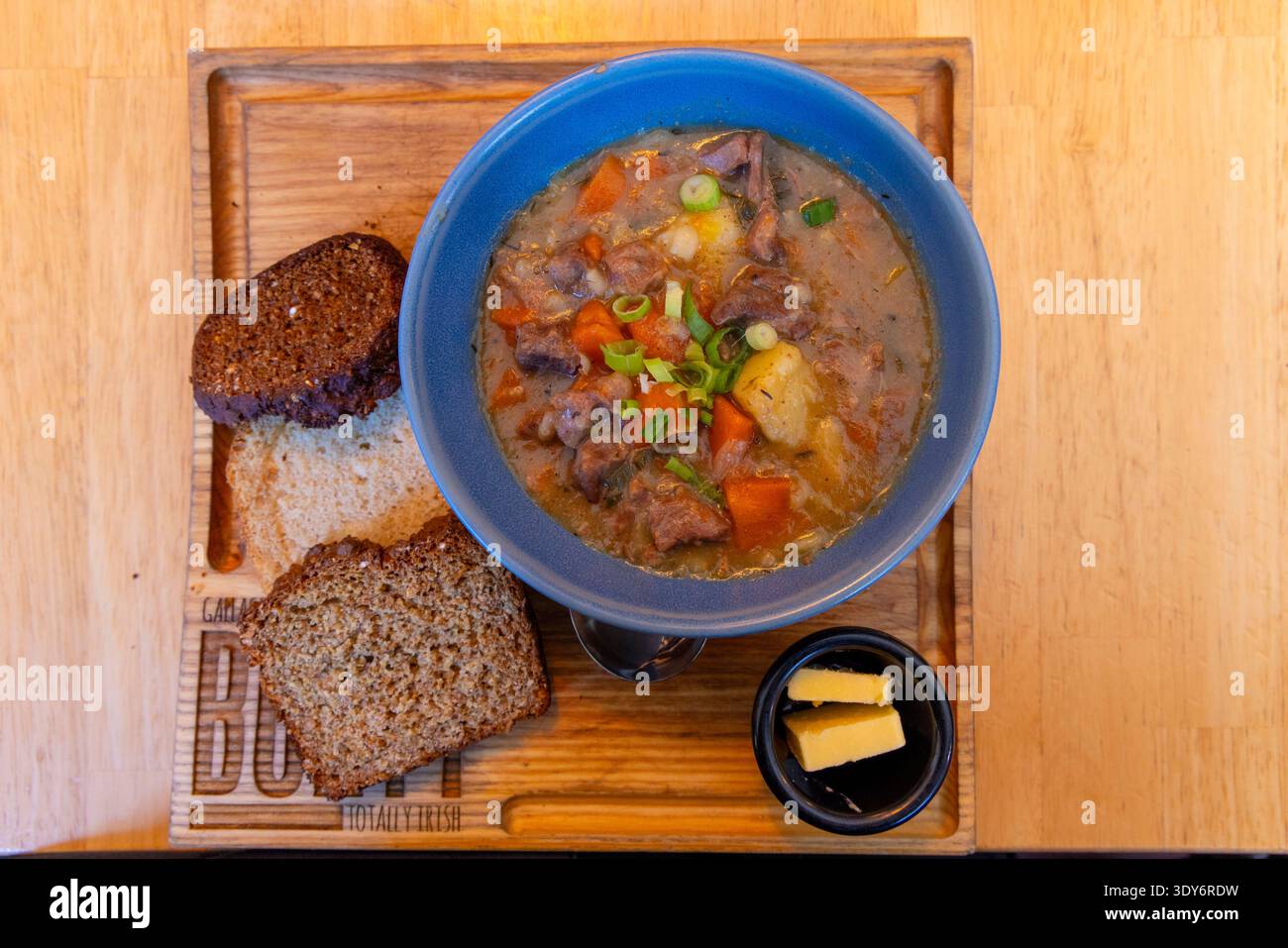 Irish stew served with brown bread and butter on a wooden tray in Dublin Stock Photo